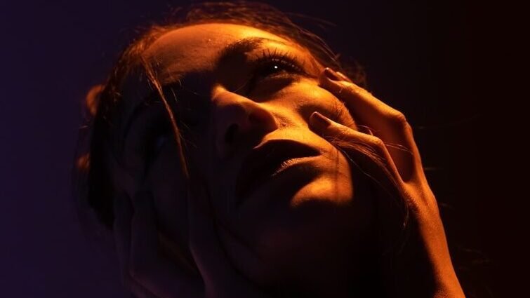 woman holds face with both hands